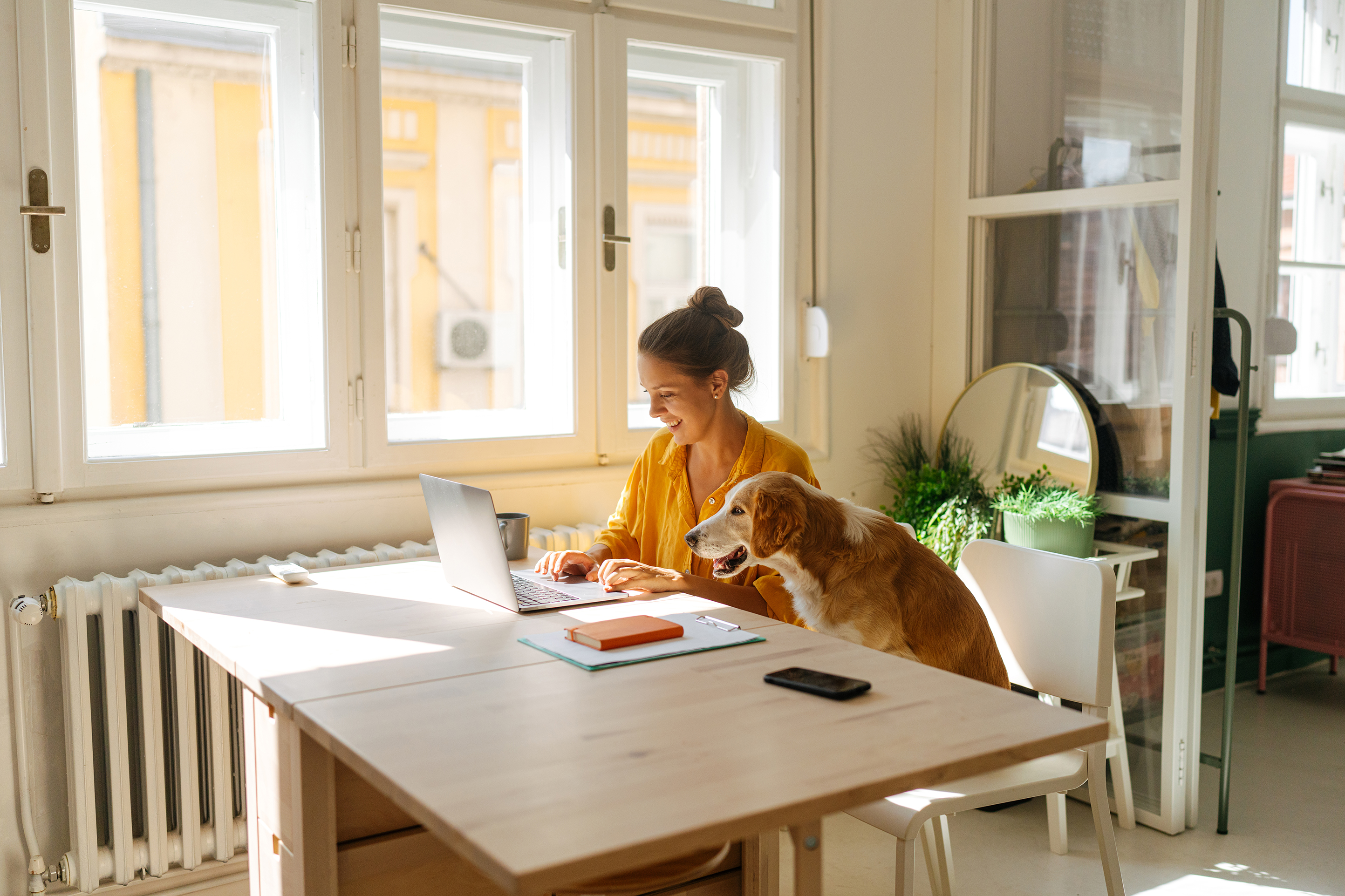 Photo of a young woman who is working from her home office, having the cutest and the cuddliest assistant - her pet dog