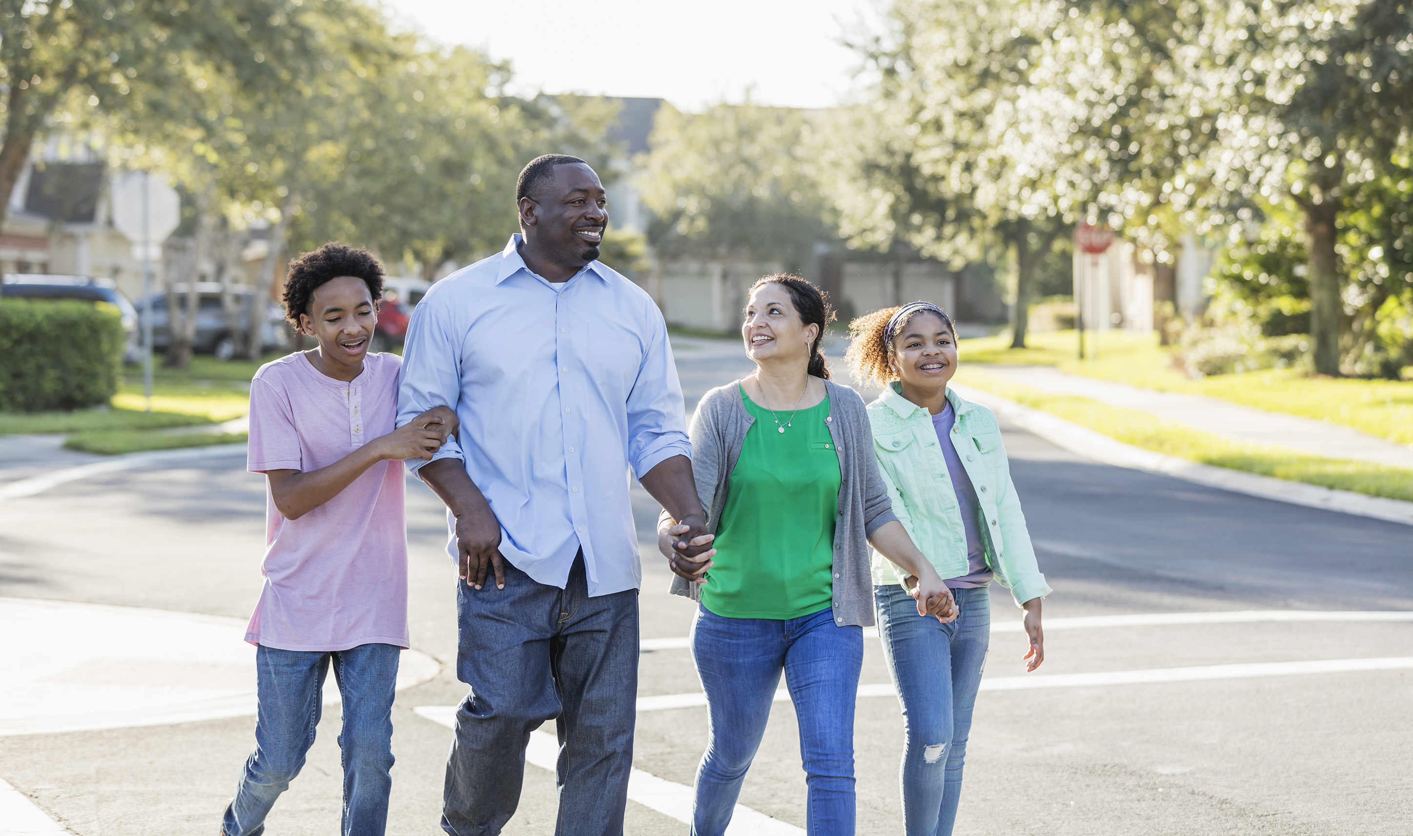 A family with two children taking a walk together in a residential neighborhood