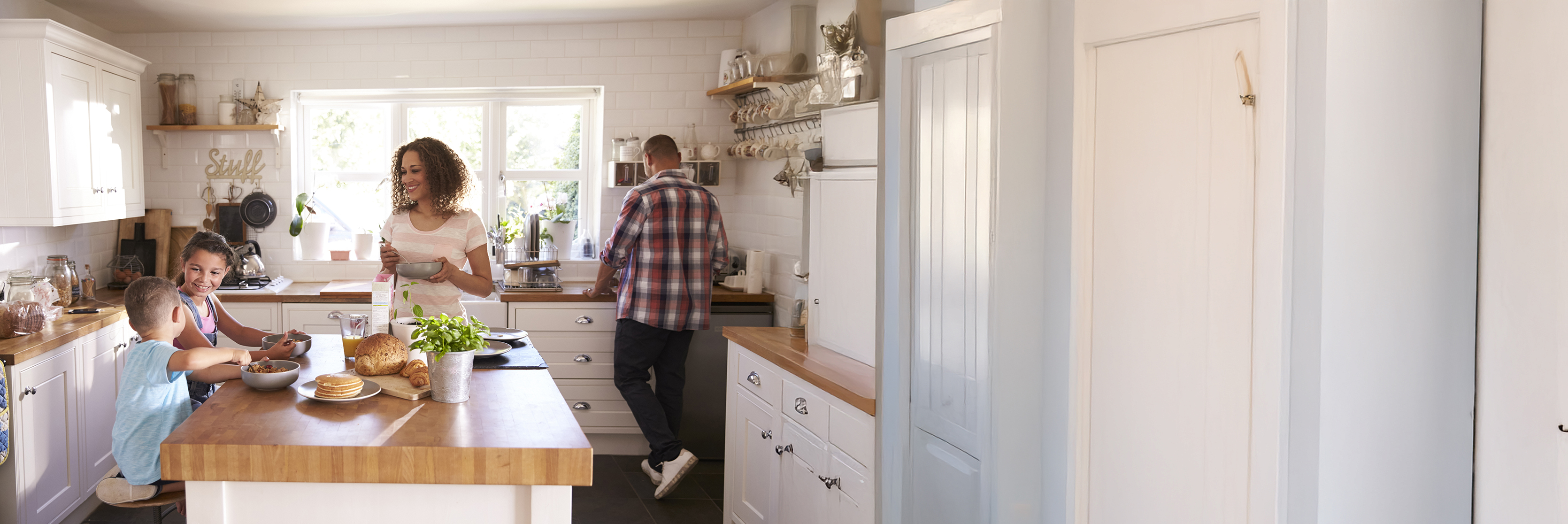 Family at home eating breakfast in kitchen together