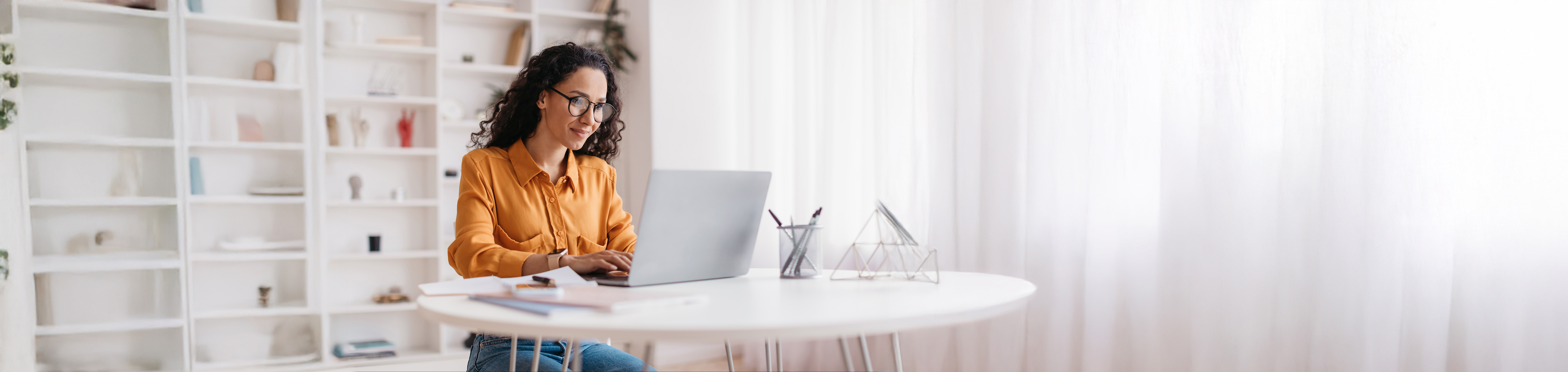 Lady using laptop working online wearing eyewear sitting at workplace in modern office